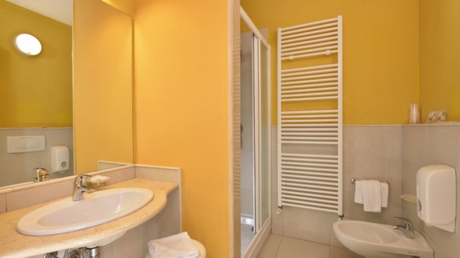 Bagno con lavabo, doccia e pareti gialle.