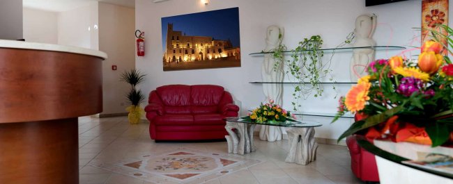 Salotto con divano rosso, piante e quadro luminoso sul muro.