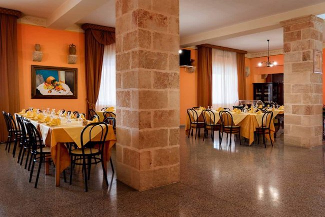 Sala da pranzo con tavoli apparecchiati e pareti color crema.