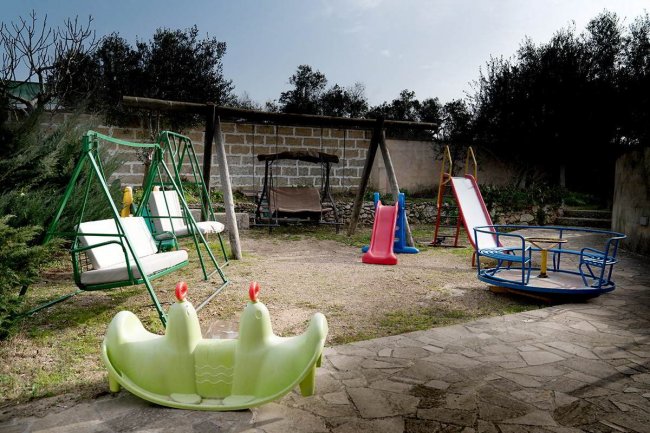 Un parco giochi con altalene, scivoli e un girello colorato.