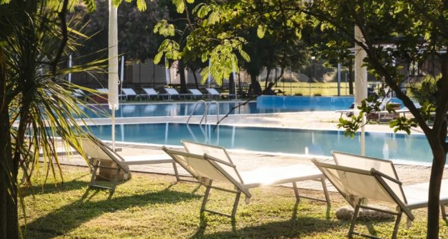 Lettini da piscina in un giardino ombreggiato.