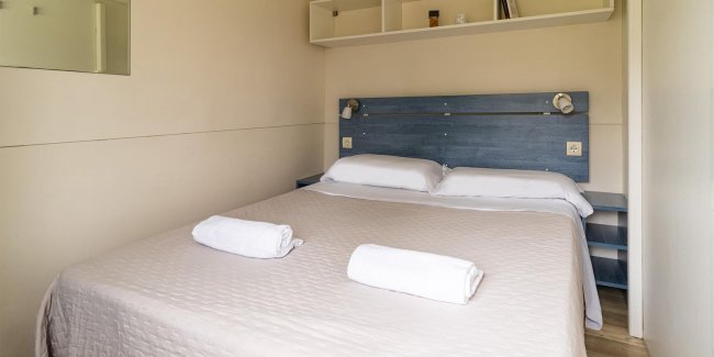 Letto matrimoniale con asciugamani piegati sopra.