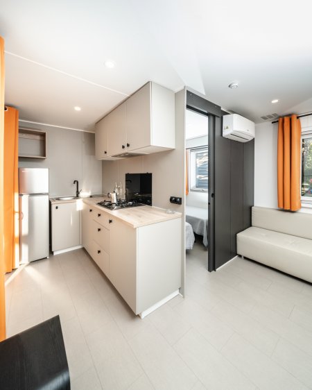 Cucina moderna con arredi neutri e divano bianco.