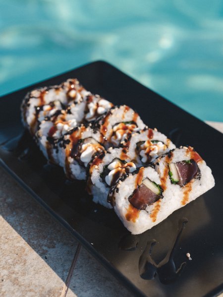 Rotoli di sushi su piatto nero.