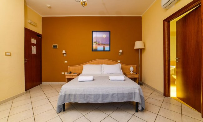 Camera con letto matrimoniale e pareti color ocra.