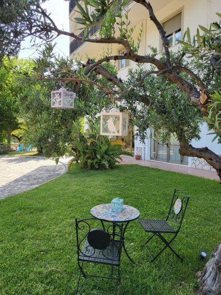 Piccolo tavolino e sedie in ferro battuto sotto un albero con lanterne appese.