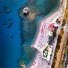 Vista aerea di una spiaggia con acqua turchese, ombrelloni e una passerella.
