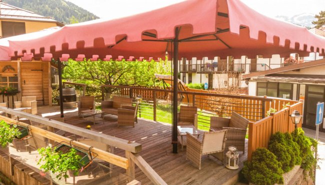 Terrazza con sedie in vimini sotto un grande ombrellone.