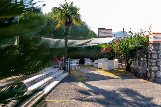 Area esterna di un hotel con sedie e tavolini sotto tende leggere.