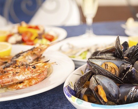 Una tavola con cozze e piatti di pesce alici e gamberi.