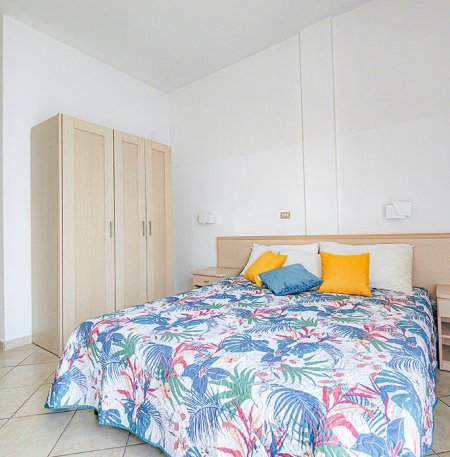 Camera da letto con letto matrimoniale e coperta colorata.