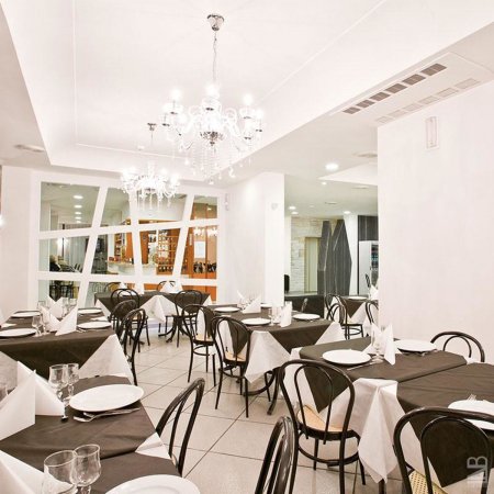 Ristorante elegante con tavoli apparecchiati e lampadari di cristallo.