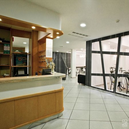 Una reception d'albergo con bancone in legno e sala attesa.