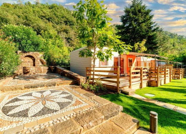 Patio con mosaico a terra, prato verde e bungalow in legno.