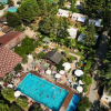 Veduta aerea di una piscina affollata circondata da alberi e strutture in un complesso turistico.