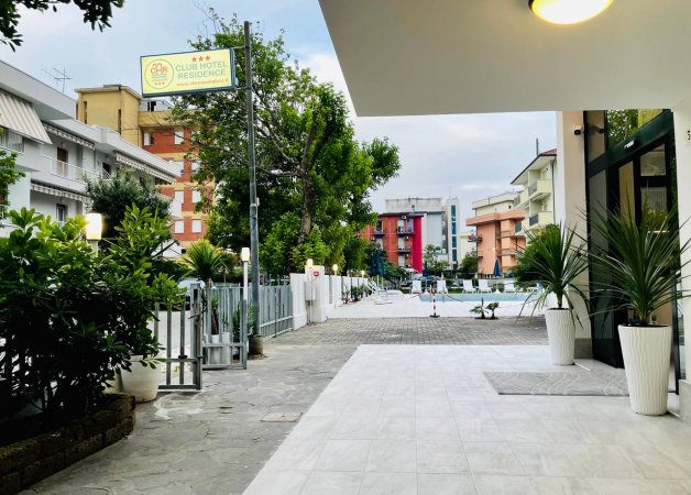 Ingresso di un hotel, con piante e cartelli.