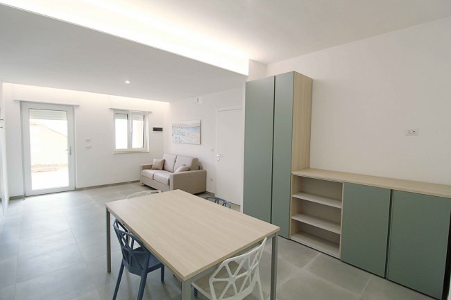 Soggiorno con tavolo, sedie e divano beige.