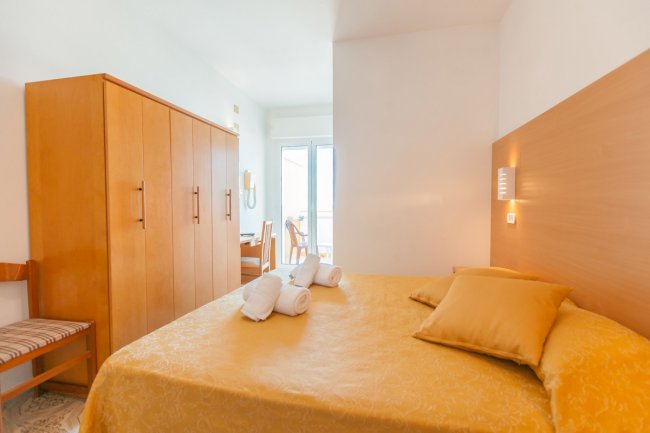 Camera con letto matrimoniale, armadio e balcone.