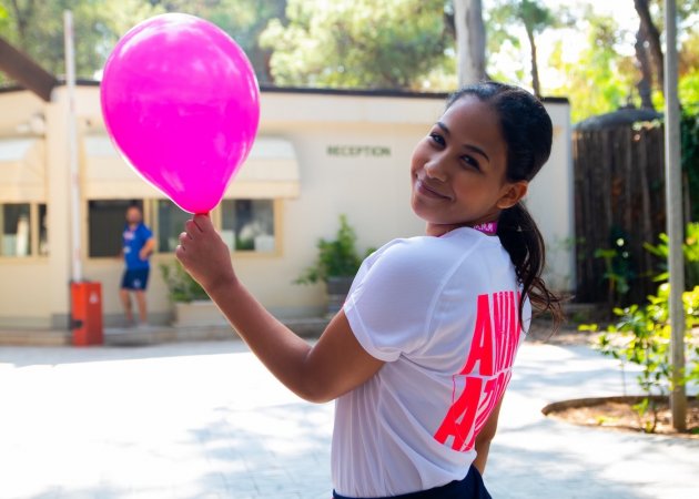 Ragazza con palloncino rosa sorridente all'aperto.
