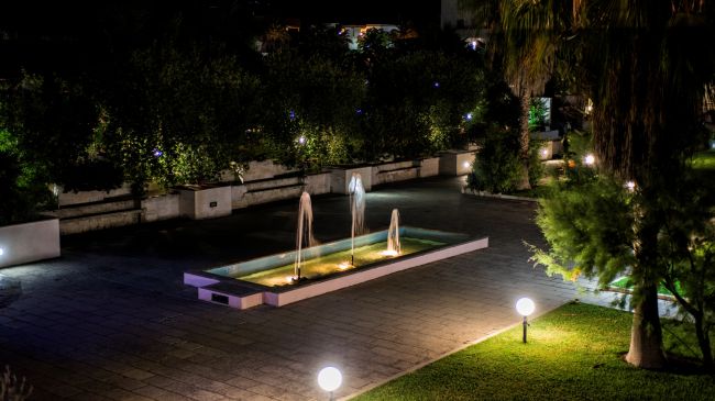 Una fontana illuminata di notte in un giardino.