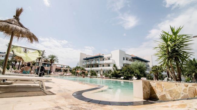 Piscina con lettini e edifici in lontananza.