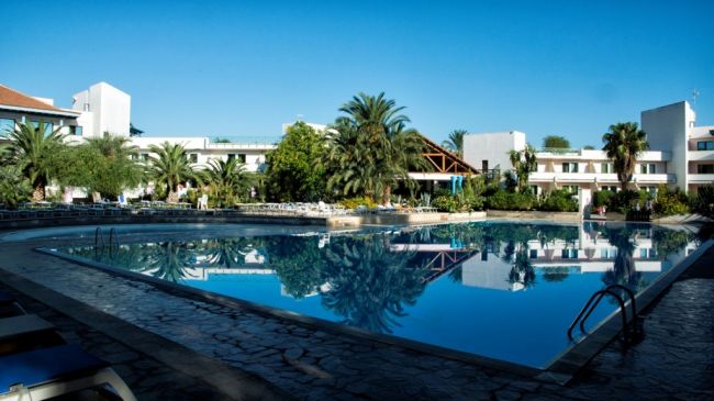 Piscina circondata da edifici bianchi e palme.