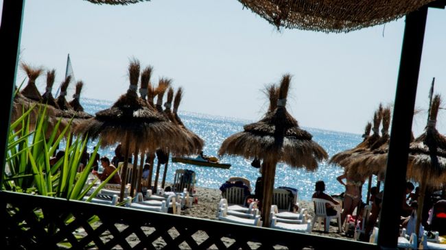 Spiaggia con ombrelloni di paglia e sdraio.