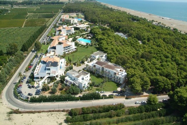 Complesso turistico con piscina e alberi vicino alla spiaggia, visto dall'alto.