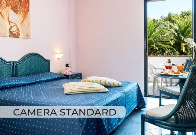 Camera luminosa con letto matrimoniale, balcone con vista su palme.