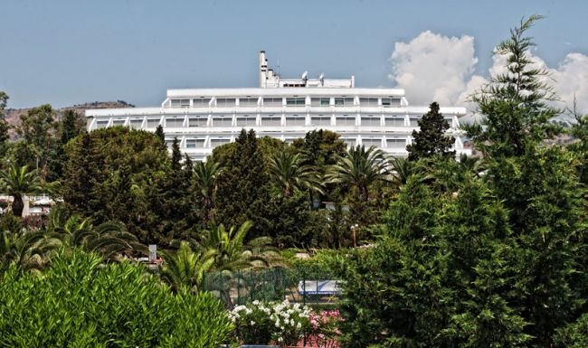 Edificio bianco tra palme e alberi verdi.