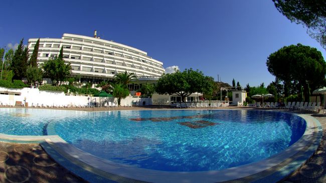 Piscina e hotel circondati da alberi.
