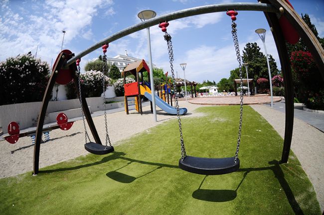 Altalene in un parco giochi con scivolo e divertimenti vari.