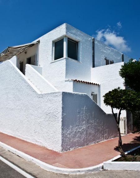 Casa bianca con scale esterne e cielo blu.