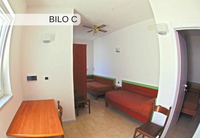 Camera con due letti singoli e ventola a soffitto.