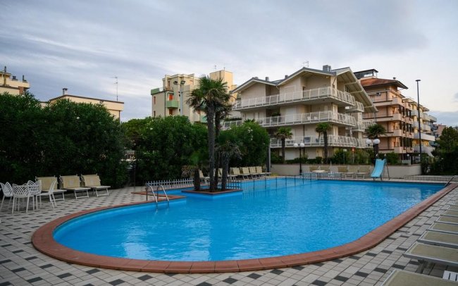 Piscina circondata da edifici e palme.