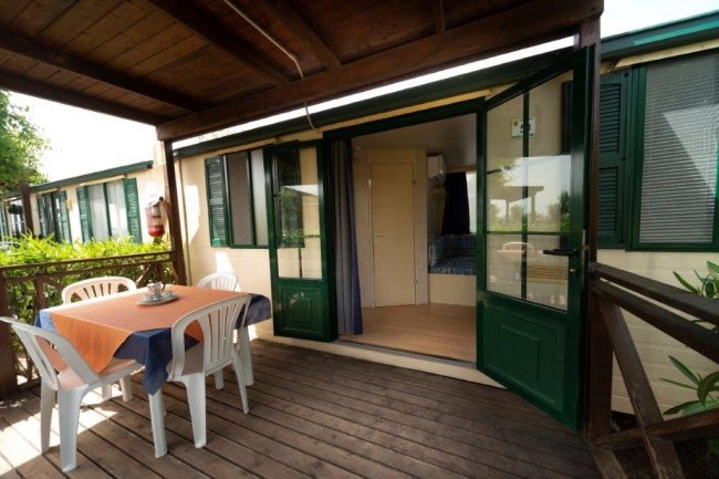 Terrazza con tavolo apparecchiato e ingresso.