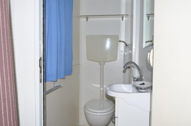 Un piccolo bagno con WC, lavandino e tenda blu.