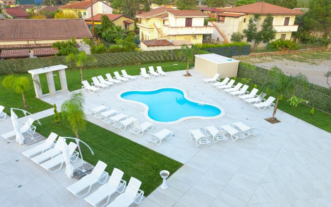 Piscina con sedie a sdraio bianche.