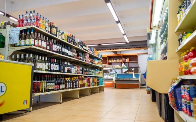 Corridoio di un supermercato con scaffali pieni di bevande e prodotti.
