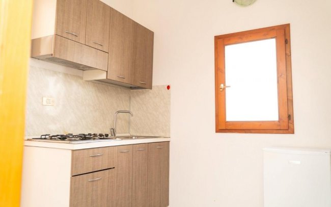 Angolo cottura compatto con mobili in legno e una finestra luminosa.