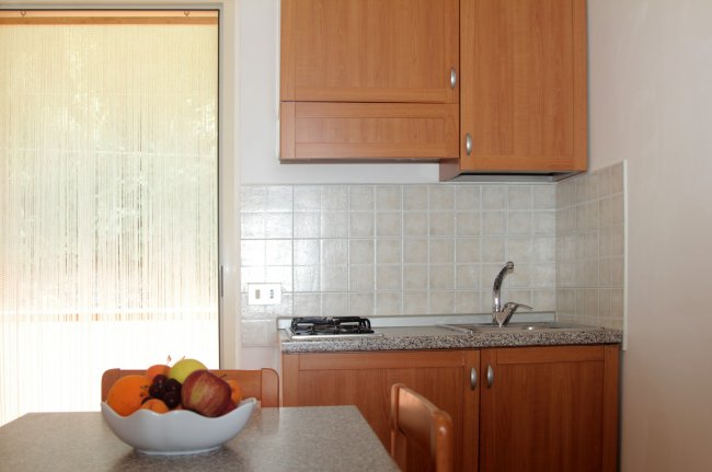 Cucina compatta con mobili in legno e frutta.