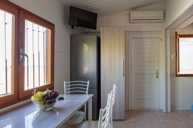 Cucina con tavolo, frigo, TV e finestra.